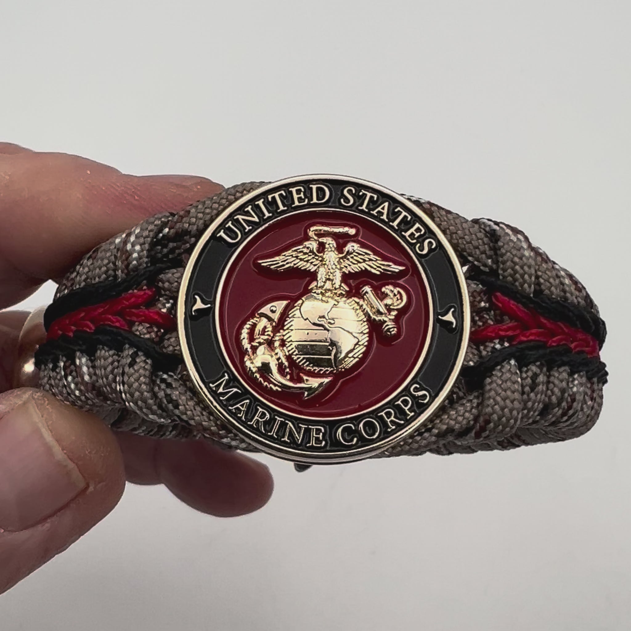 Thick, rigid and comfortable braided United States Marine Corps bracelet featuring a 24K gold plated USMC Eagle Globe and Anchor medallion, a gold Cobra style tactical buckle and woven with Desert Camo 550 paracord and black and Imperial Red micro cord.