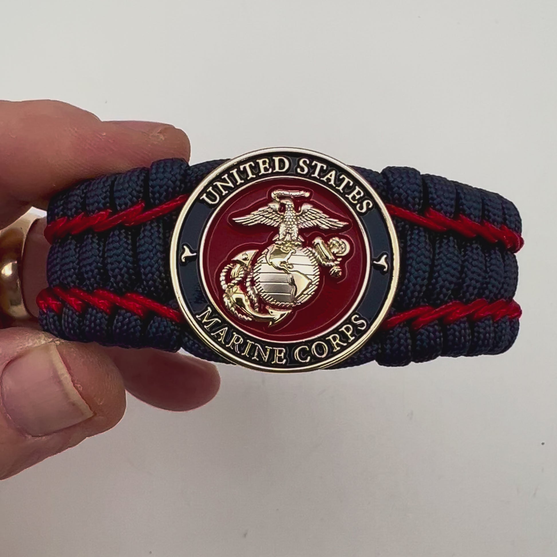 Thick and comfortable braided United States Marine Corps bracelet featuring a 24K gold and silver plated USMC officer Eagle Globe and Anchor medallion, a Cobra style tactical buckle and woven with gold 550 paracord and Imperial Red micro cord.