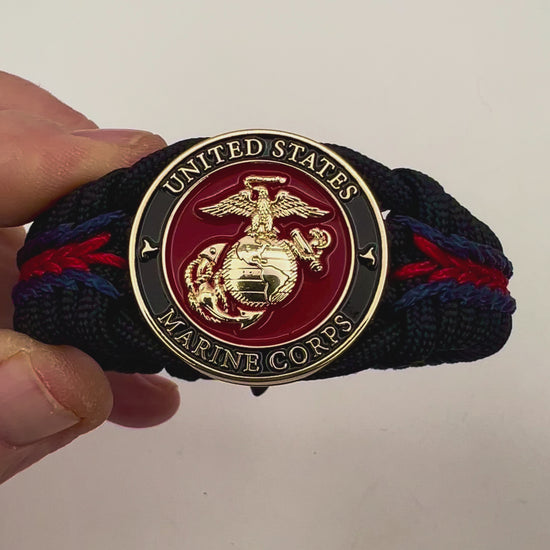 Thick, rigid and comfortable braided United States Marine Corps bracelet featuring a 24K gold plated USMC officer Eagle Globe and Anchor medallion, a black Cobra style tactical buckle and woven with black 550, Imperial red and Navy Blue micro paracord.