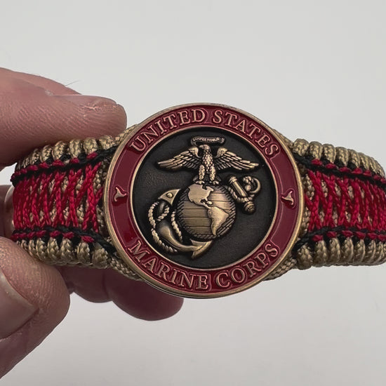 Thin, medium width, flexible and comfortable braided United States Marine Corps bracelet featuring a 24K antique gold plated USMC Eagle Globe and Anchor medallion, a gold Cobra style tactical buckle and woven with gold Type-1 paracord and Imperial Red and Black nano cord.