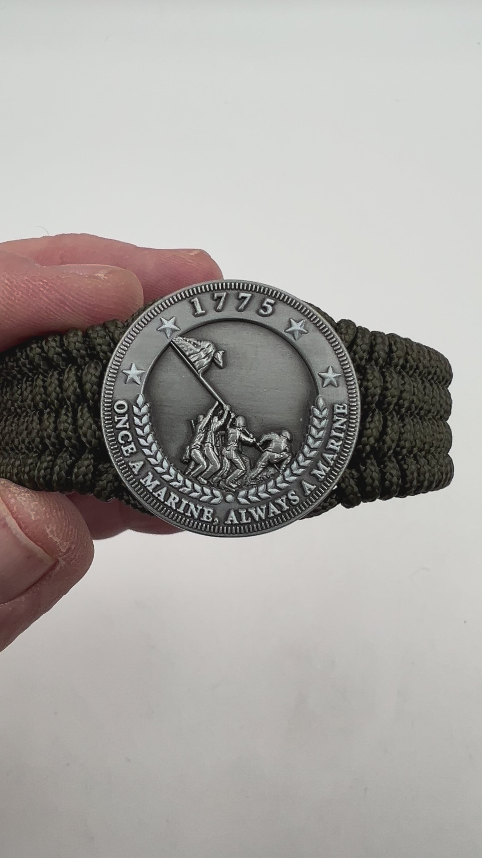 Thin, wide, flexible and comfortable braided United States Marine Corps Iwo Jima bracelet featuring an antique silver plated Iwo Jima flag raising medallion, a silver Cobra style tactical buckle and woven with olive drab type-1 paracord.