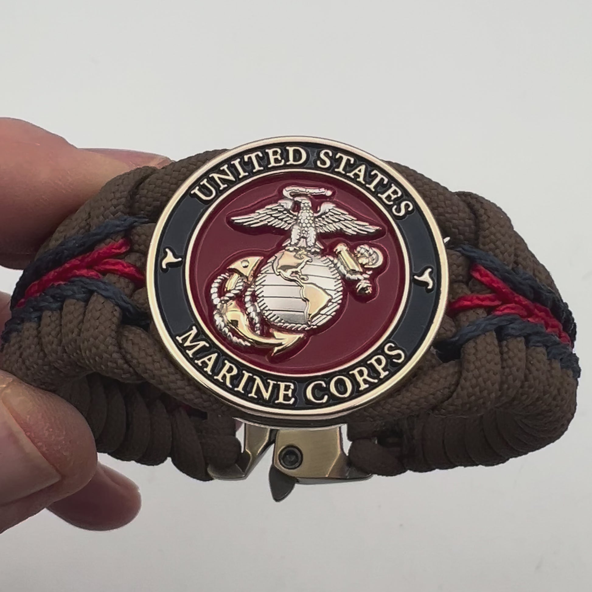 Thick, semi-rigid and comfortable braided United States Marine Corps bracelet featuring a 24K gold and silver plated USMC officer Eagle Globe and Anchor medallion, a Cobra style tactical buckle and woven with Coyote brown 550, Navy blue and Imperial red micro paracord.