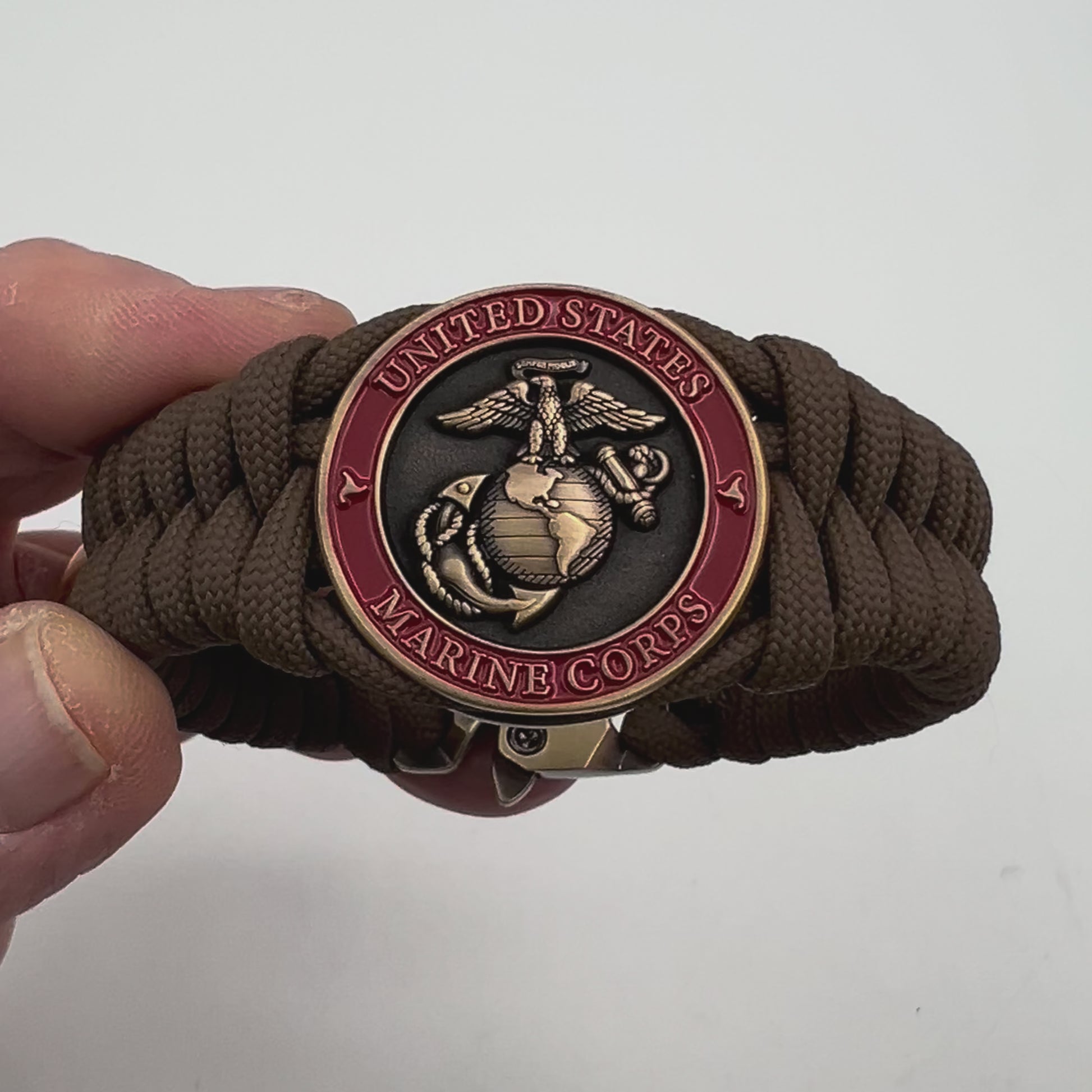 Thick, medium width, semi-rigid and comfortable braided United States Marine Corps bracelet featuring a 24K antique gold plated USMC Eagle Globe and Anchor medallion, a gold Cobra style tactical buckle and woven with Coyote Brown 550 paracord 
