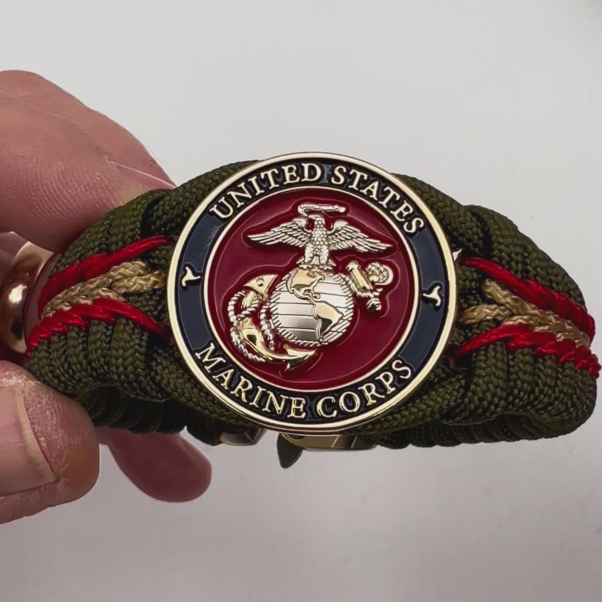 Thick, semi-rigid and comfortable braided United States Marine Corps bracelet featuring a 24K gold and silver plated USMC officer Eagle Globe and Anchor medallion, a gold Cobra style tactical buckle and woven with olive drab 550 and gold micro paracord.