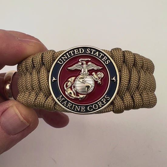 Thick and comfortable braided United States Marine Corps bracelet featuring a 24K gold and silver plated USMC officer Eagle Globe and Anchor medallion, a Cobra style tactical buckle and woven with gold 550 paracord.