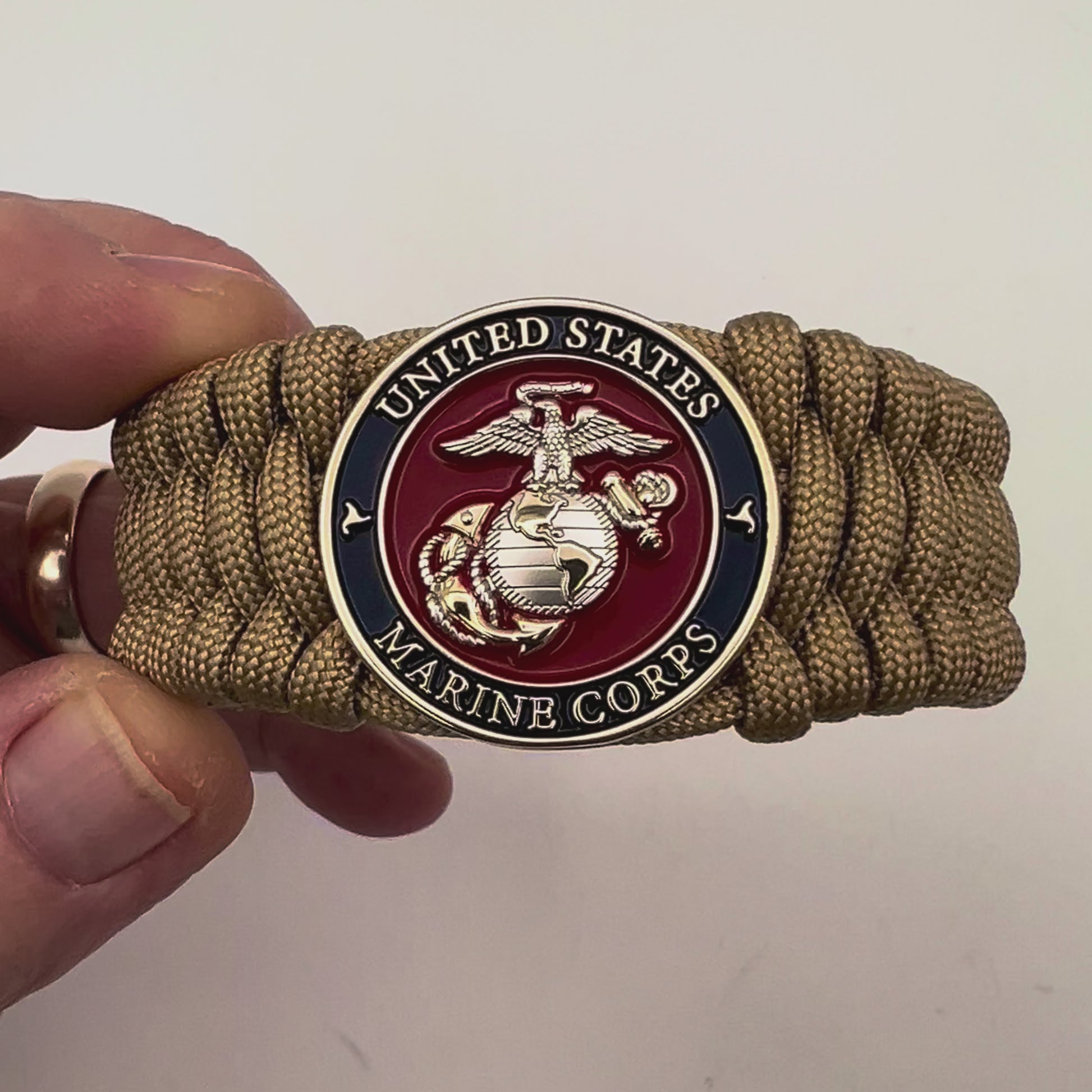 Thick and comfortable braided United States Marine Corps bracelet featuring a 24K gold and silver plated USMC officer Eagle Globe and Anchor medallion, a Cobra style tactical buckle and woven with gold 550 paracord.