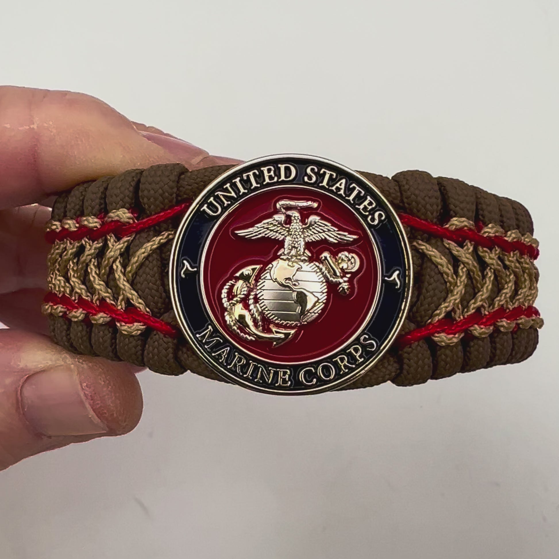 Thick and comfortable braided United States Marine Corps bracelet featuring a 24K gold and silver plated USMC officer Eagle Globe and Anchor medallion, a Cobra style tactical buckle and woven with Coyote Brown 550 paracord and Imperial Red and gold micro cord.