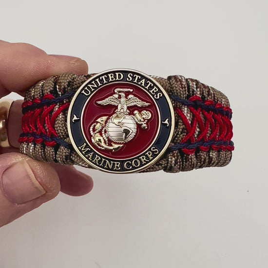 Thick and comfortable braided United States Marine Corps bracelet featuring a 24K gold and silver plated USMC officer Eagle Globe and Anchor medallion, a gold Cobra style tactical buckle and woven with Desert Camo 550 paracord and Imperial Red and Navy Blue micro cord.