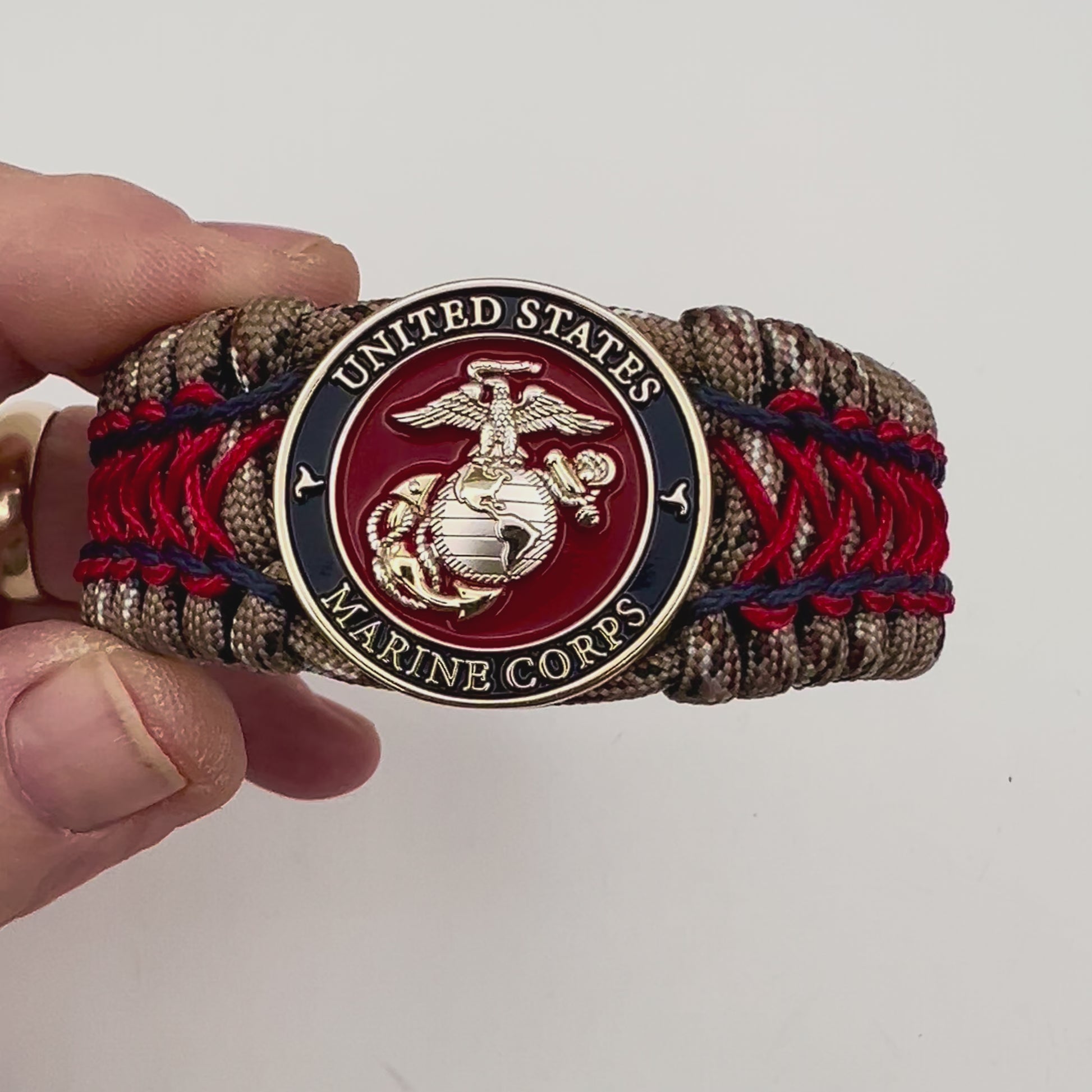 Thick and comfortable braided United States Marine Corps bracelet featuring a 24K gold and silver plated USMC officer Eagle Globe and Anchor medallion, a gold Cobra style tactical buckle and woven with Desert Camo 550 paracord and Imperial Red and Navy Blue micro cord.