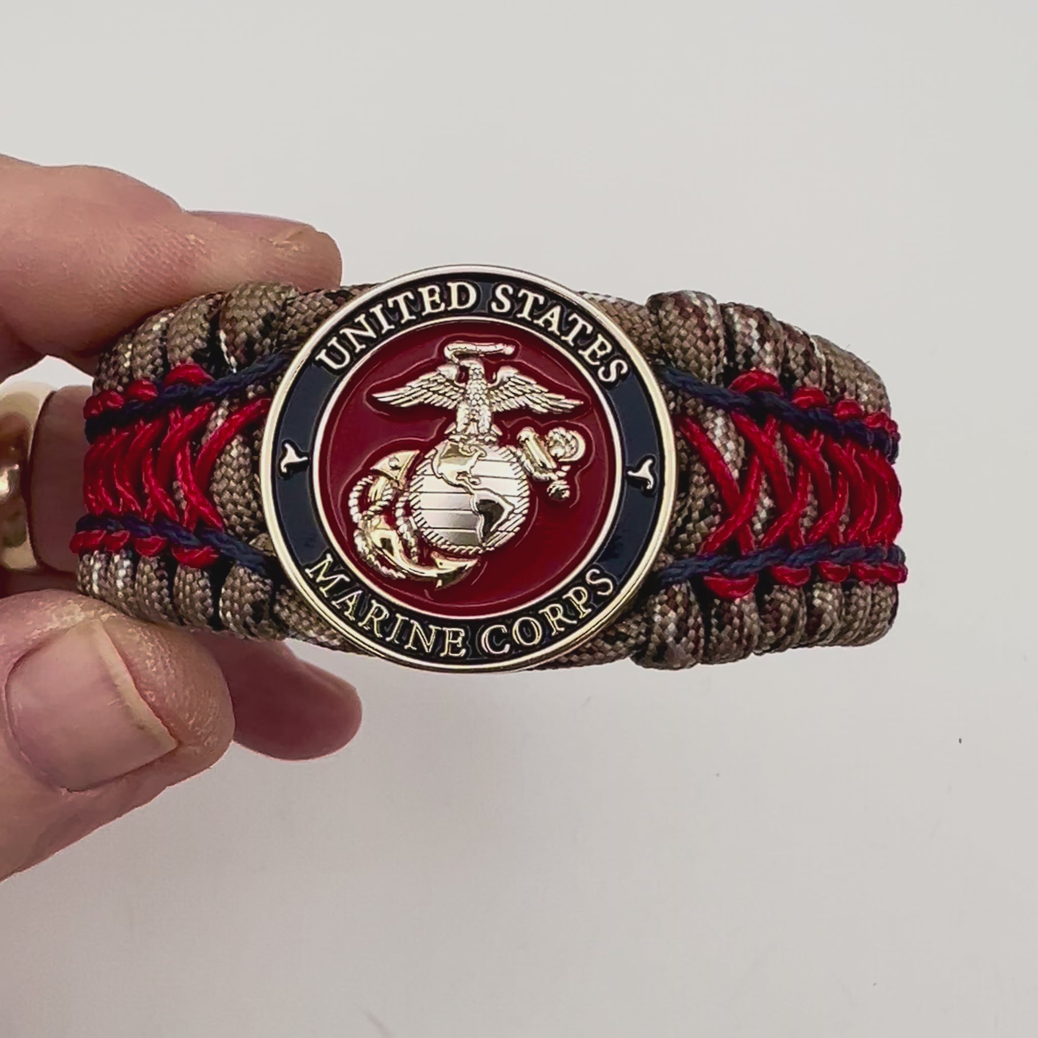 Thick and comfortable braided United States Marine Corps bracelet featuring a 24K gold and silver plated USMC officer Eagle Globe and Anchor medallion, a gold Cobra style tactical buckle and woven with Desert Camo 550 paracord and Imperial Red and Navy Blue micro cord.