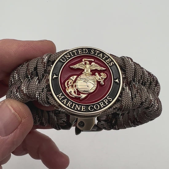 Thick, semi-rigid and comfortable braided United States Marine Corps bracelet featuring a 24K gold plated USMC Eagle Globe and Anchor medallion, a gold Cobra style tactical buckle and woven with Desert Camo 550 paracord.