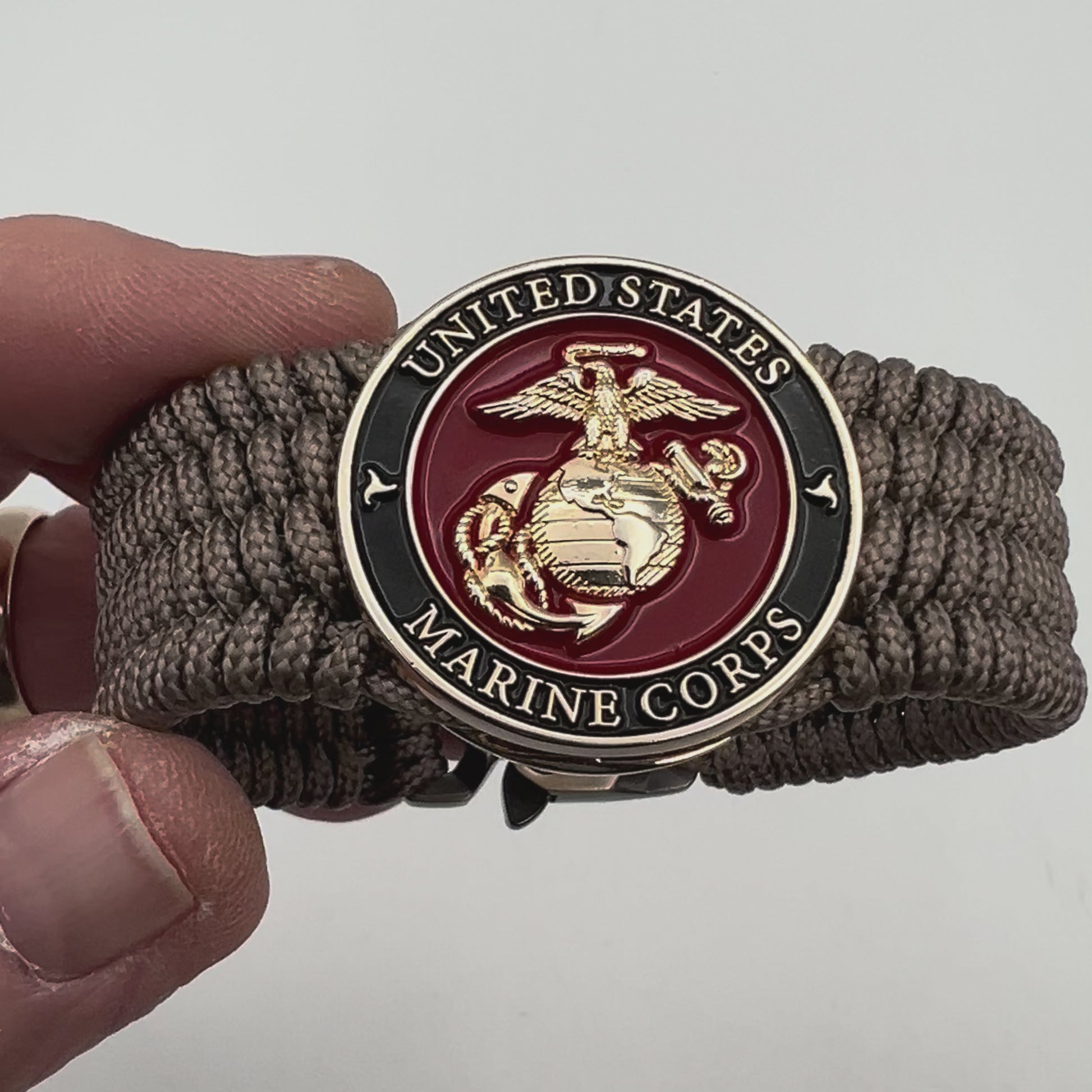 Thin, medium width, flexible and comfortable braided United States Marine Corps bracelet featuring a 24K gold plated USMC officer Eagle Globe and Anchor medallion, a gold Cobra style tactical buckle and woven with Tan Type-1 paracord.