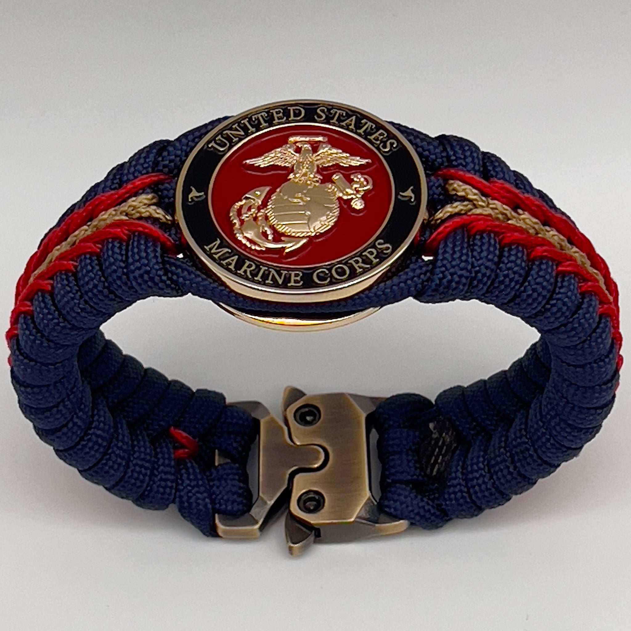 Thick, rigid and comfortable braided United States Marine Corps bracelet featuring a 24K gold plated USMC Eagle Globe and Anchor medallion, a gold Cobra style tactical buckle and woven withNavy Blue 550 paracord and Imperial Red micro cord.