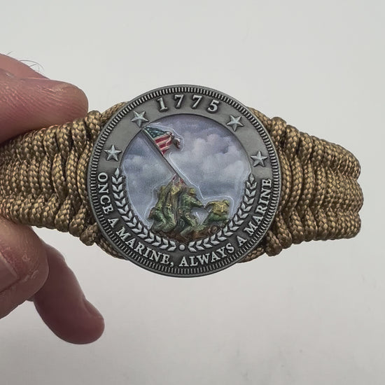 Thin, narrow, flexible and comfortable braided United States Marine Corps Iwo Jima bracelet featuring an antique silver plated UV painted Iwo Jima flag raising medallion, a gold Cobra style tactical buckle and woven with gold type-1 paracord.