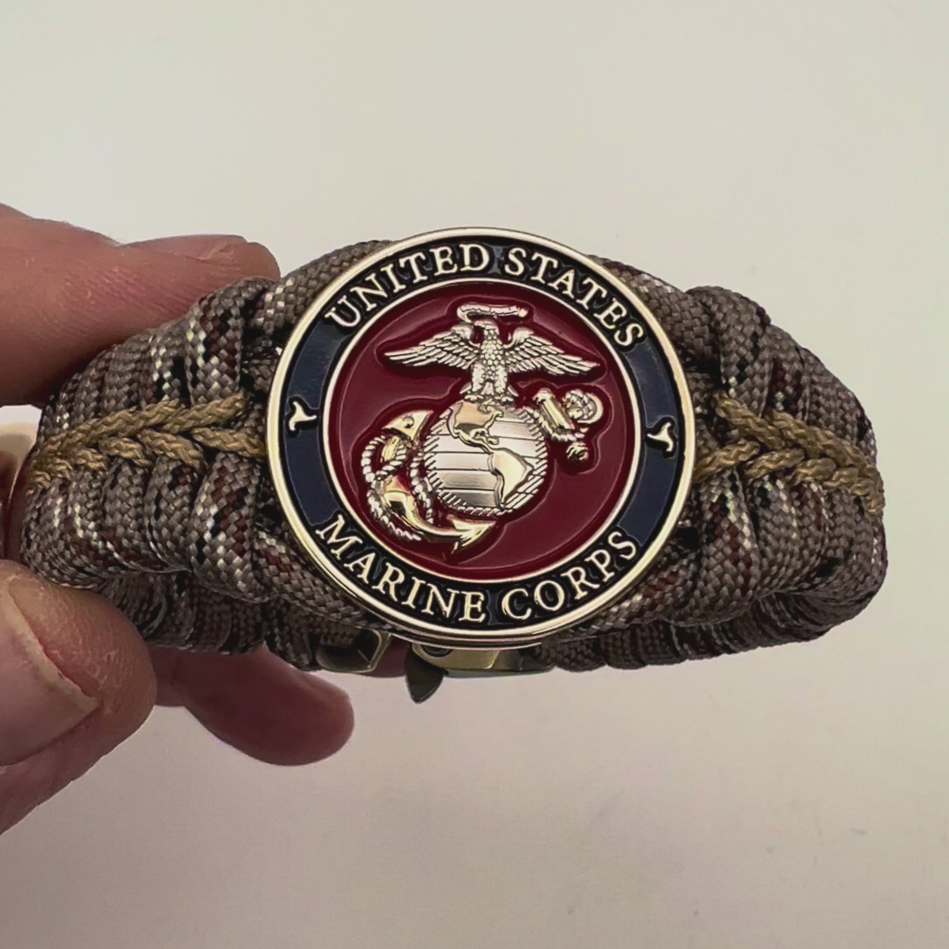 Thick and comfortable braided United States Marine Corps bracelet featuring a 24K gold and silver plated USMC officer Eagle Globe and Anchor medallion, a Cobra style tactical buckle and woven with Desert Camo 550 paracord gold micro cord.