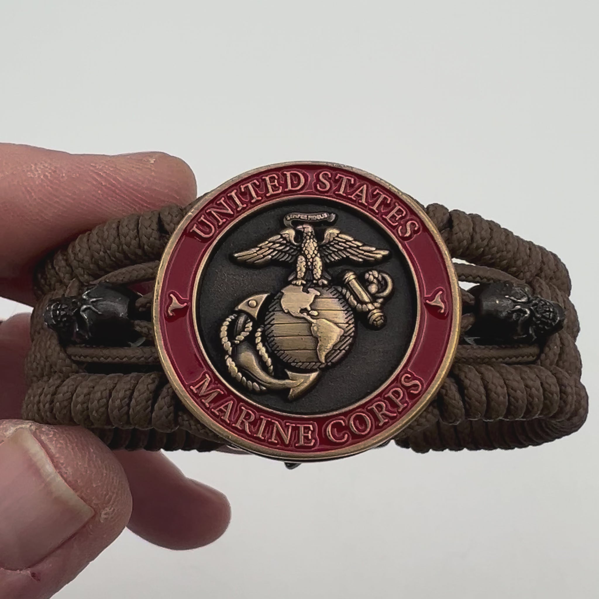 Thin, medium width, flexible and comfortable braided United States Marine Corps bracelet featuring a 24K antique gold plated USMC officer Eagle Globe and Anchor medallion, two black skulls, a black Cobra style tactical buckle and woven with Coyote Brown Type-1 paracord.