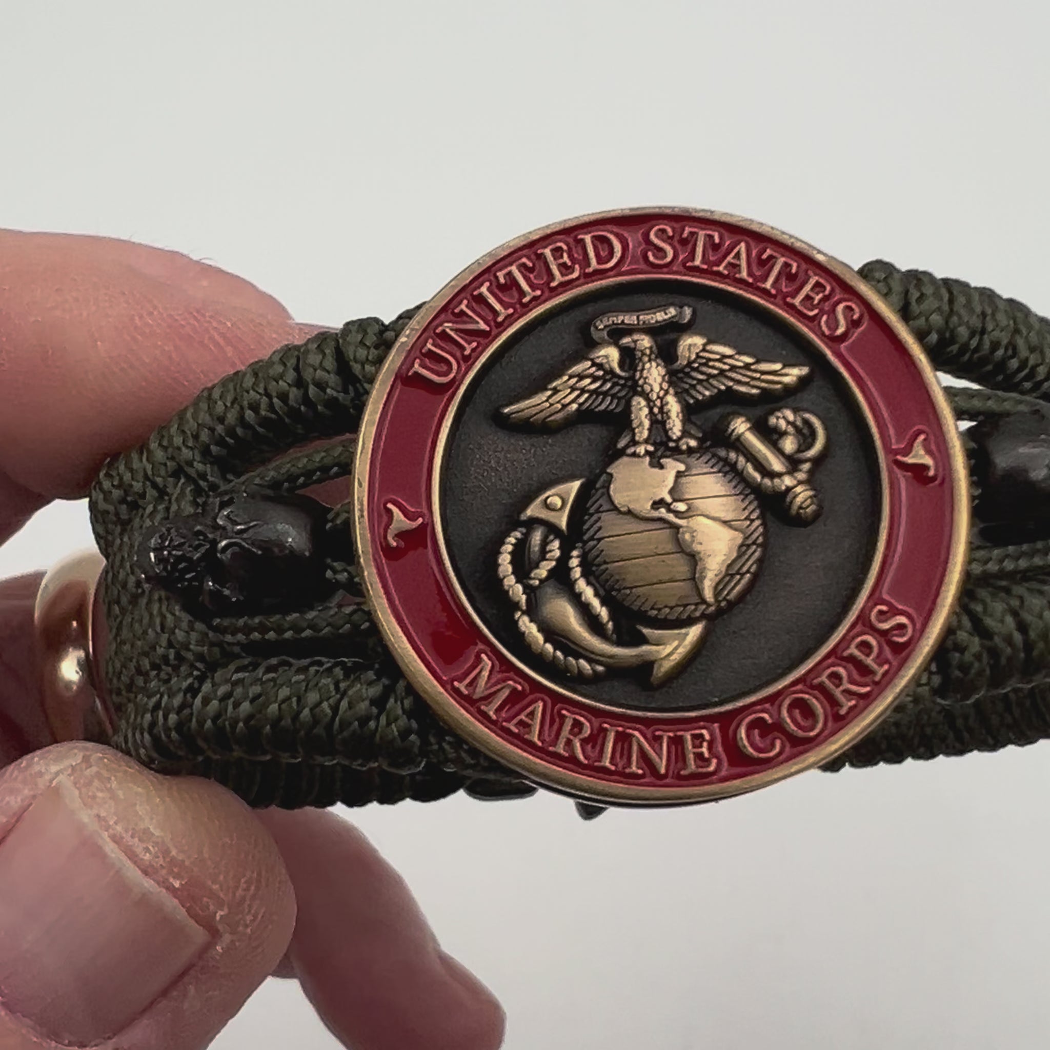 Thin, medium width, flexible and comfortable braided United States Marine Corps bracelet featuring a 24K antique gold plated USMC officer Eagle Globe and Anchor medallion, two black skulls, a black Cobra style tactical buckle and woven with Olive Drab Type-1 paracord.