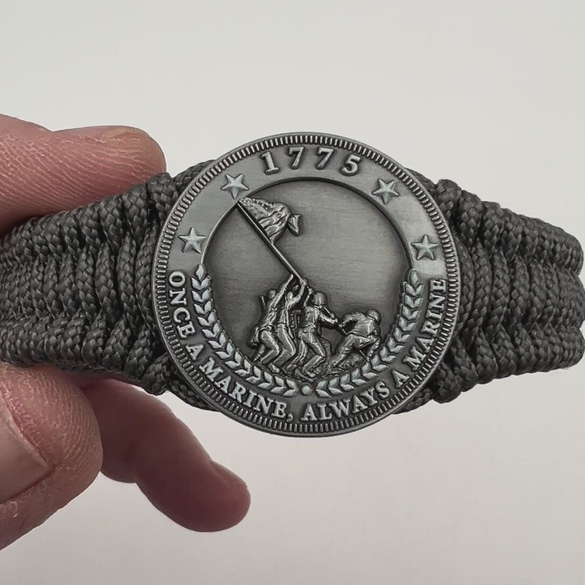 Thin, narrow, flexible and comfortable braided United States Marine Corps Iwo Jima bracelet featuring an antique silver plated Iwo Jima flag raising medallion, a silver Cobra style tactical buckle and woven with Charcoal Gray type-1 paracord.
