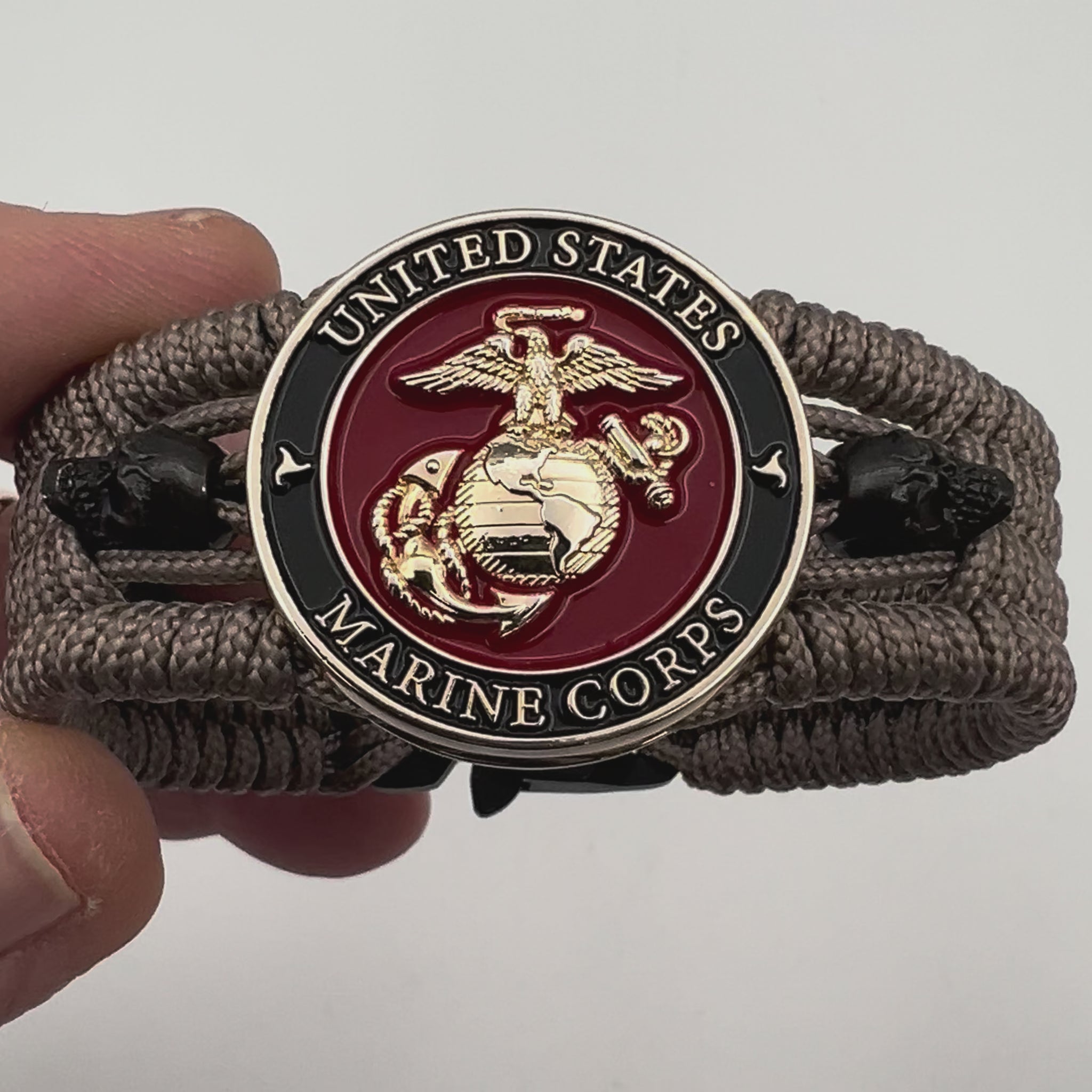 Thin, medium width, flexible and comfortable braided United States Marine Corps bracelet featuring a 24K gold plated USMC officer Eagle Globe and Anchor medallion, two black skulls, a black Cobra style tactical buckle and woven with tan Type-1 paracord.