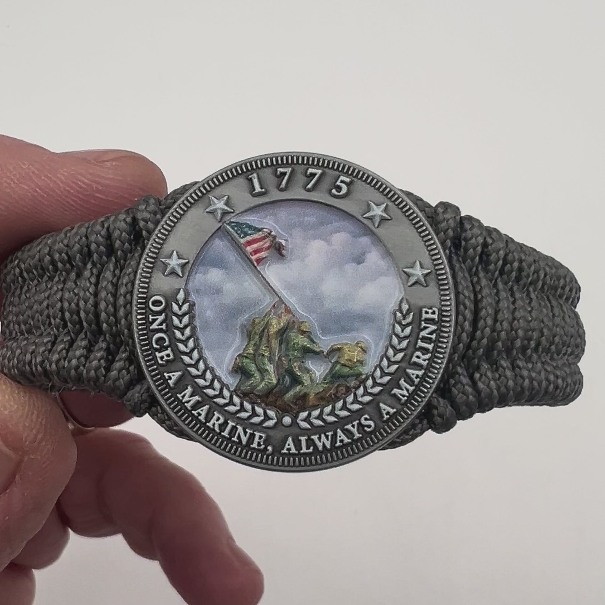 Thin, narrow, flexible and comfortable braided United States Marine Corps Iwo Jima bracelet featuring an antique silver plated UV painted Iwo Jima flag raising medallion, a silver Cobra style tactical buckle and woven with Charcoal Gray type-1 paracord.