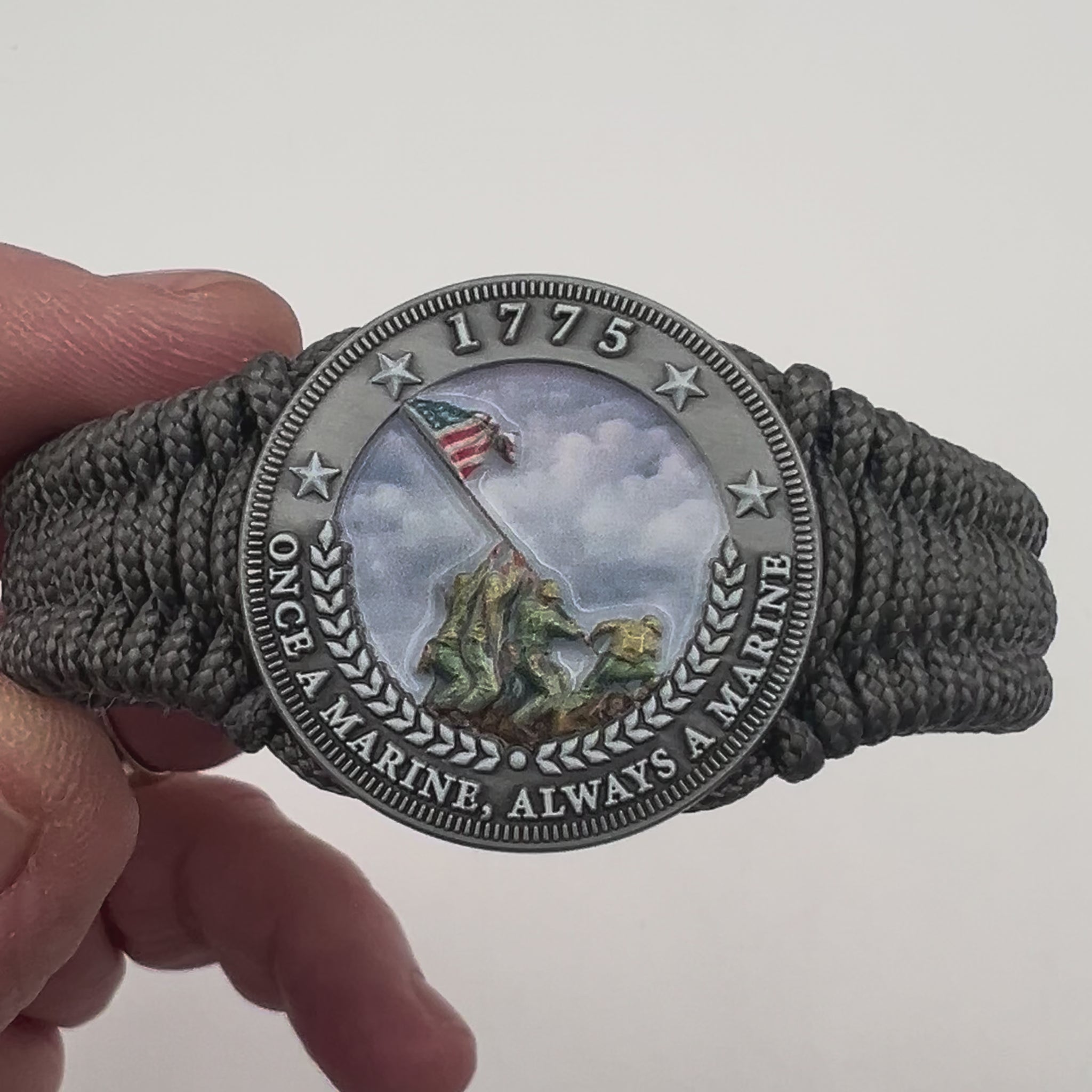 Thin, narrow, flexible and comfortable braided United States Marine Corps Iwo Jima bracelet featuring an antique silver plated UV painted Iwo Jima flag raising medallion, a silver Cobra style tactical buckle and woven with Charcoal Gray type-1 paracord.