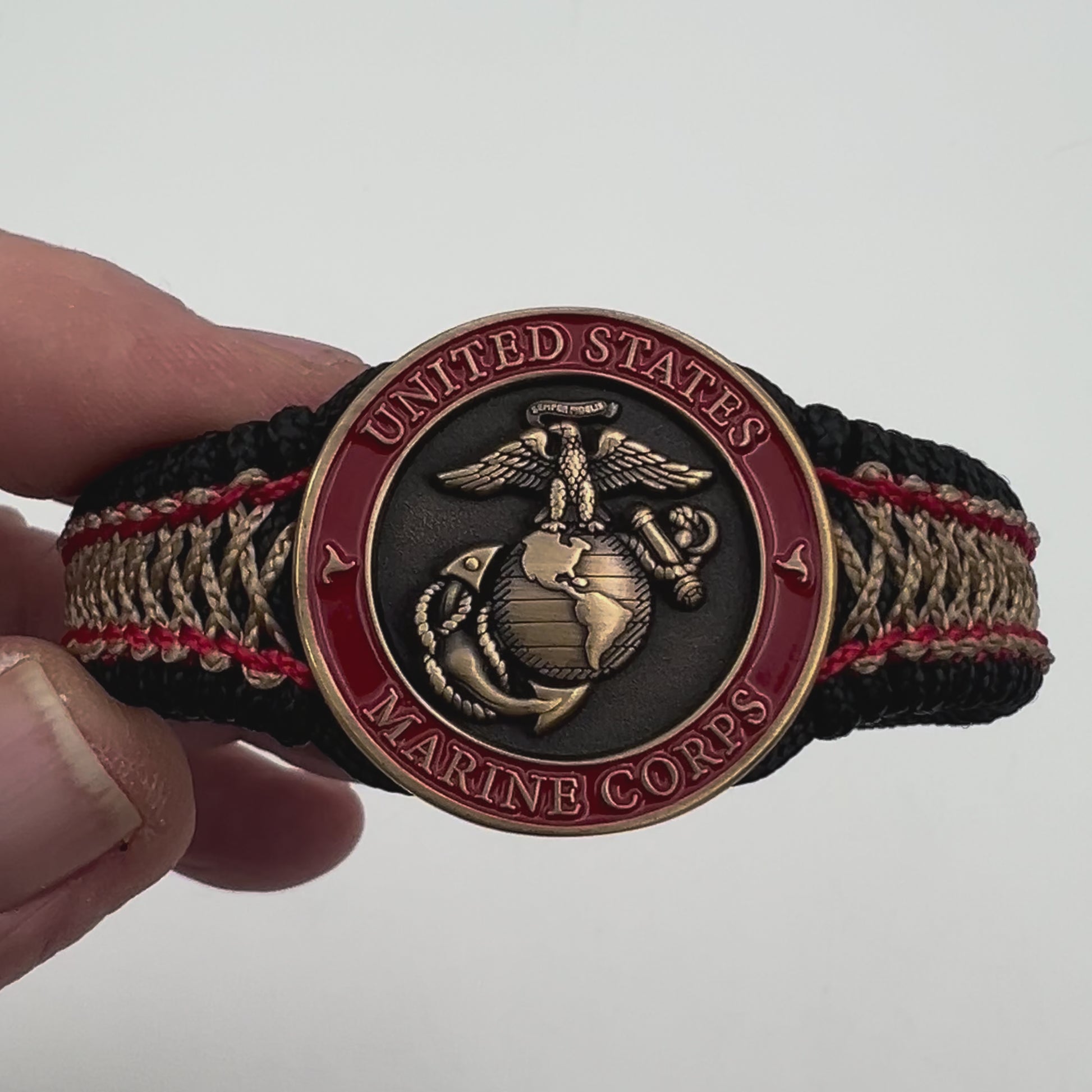 Thin, narrow, very thin and flexible and comfortable braided United States Marine Corps bracelet featuring a 24K antique gold plated USMC Eagle Globe and Anchor medallion, a black Cobra style tactical buckle and woven with black Type-1 paracord and Imperial Red and GOld nano cord.