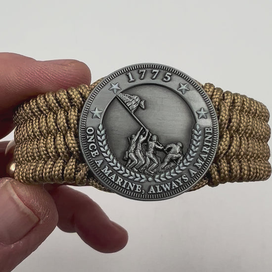Thin, wide, flexible and comfortable braided United States Marine Corps Iwo Jima bracelet featuring an antique silver plated Iwo Jima flag raising medallion, a gold Cobra style tactical buckle and woven with gold Type-1 paracord.