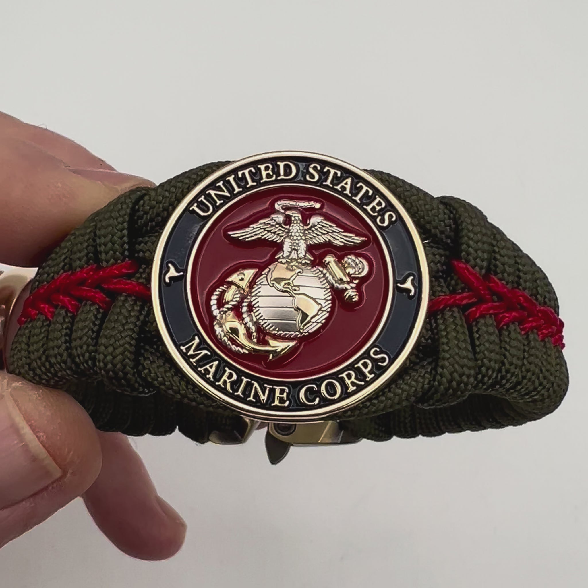 Thick, semi-rigid and comfortable braided United States Marine Corps bracelet featuring a 24K gold and silver plated USMC officer Eagle Globe and Anchor medallion, a gold Cobra style tactical buckle and woven with olive drab 550 and Imperial red micro paracord.