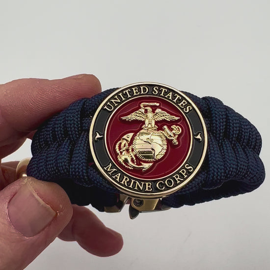 Thick, semi-rigid and comfortable braided United States Marine Corps bracelet featuring a 24K gold plated USMC Eagle Globe and Anchor medallion, a gold Cobra style tactical buckle and woven with Navy Blue 550 paracord.