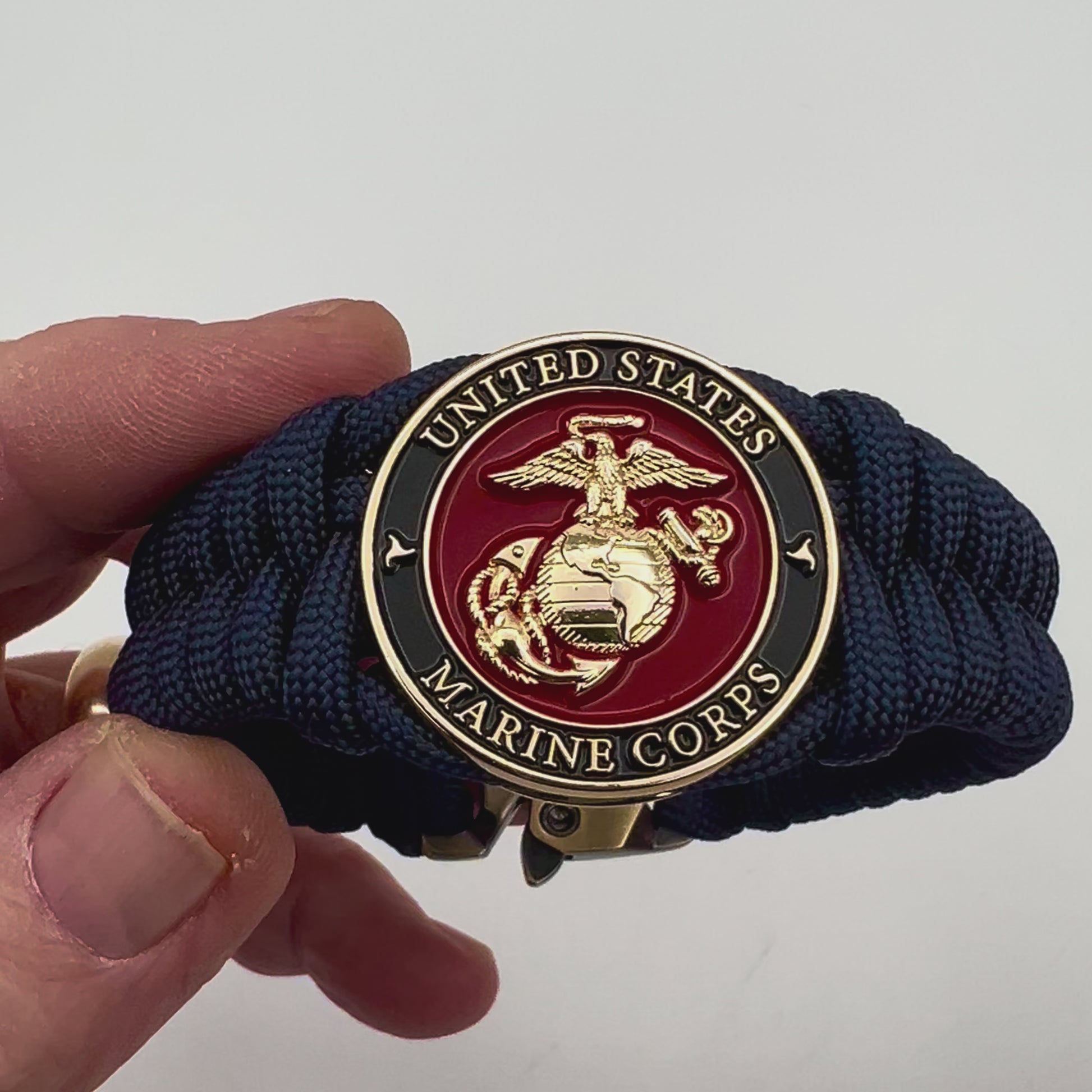 Thick, semi-rigid and comfortable braided United States Marine Corps bracelet featuring a 24K gold plated USMC Eagle Globe and Anchor medallion, a gold Cobra style tactical buckle and woven with Navy Blue 550 paracord.