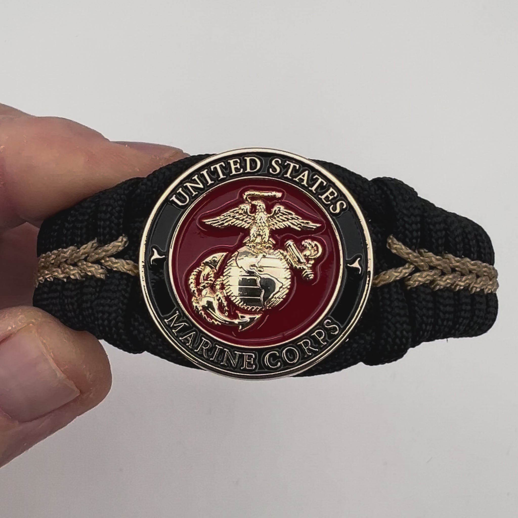 Thick, semi-rigid and comfortable braided United States Marine Corps bracelet featuring a 24K gold plated USMC officer Eagle Globe and Anchor medallion, a black Cobra style tactical buckle and woven with black 550 paracord and gold micro cord.