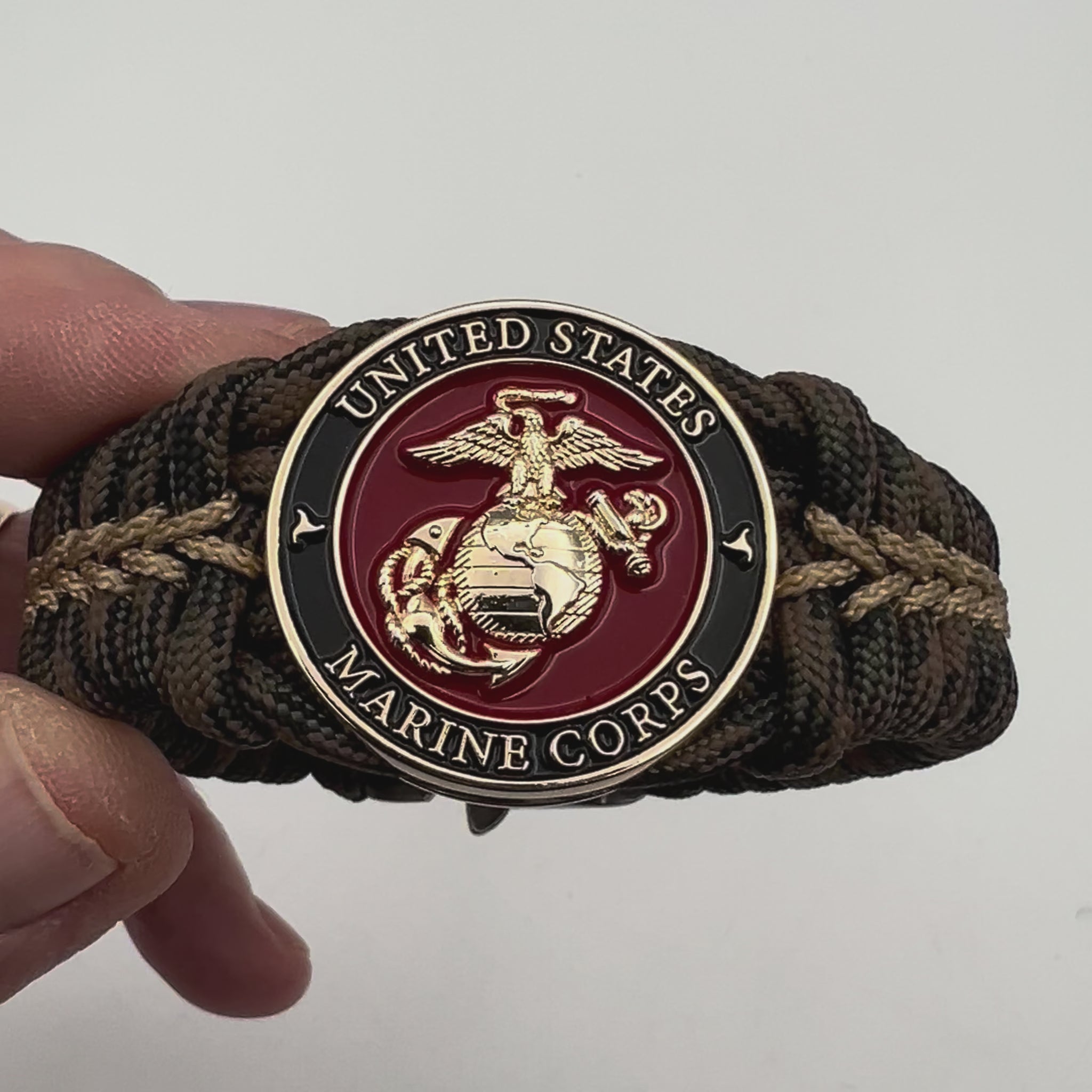 Thick, rigid and comfortable braided United States Marine Corps bracelet featuring a 24K gold plated USMC Eagle Globe and Anchor medallion, a gold Cobra style tactical buckle and woven with Woodland 550 paracord.