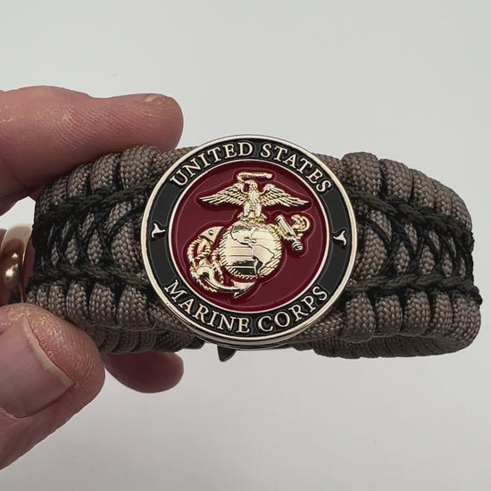 Thick, wide, rigid and comfortable braided United States Marine Corps bracelet featuring a 24K gold plated USMC Eagle Globe and Anchor medallion, a gold Cobra style tactical buckle and woven with tan 550 paracord, olive drab micro and black nano cord.