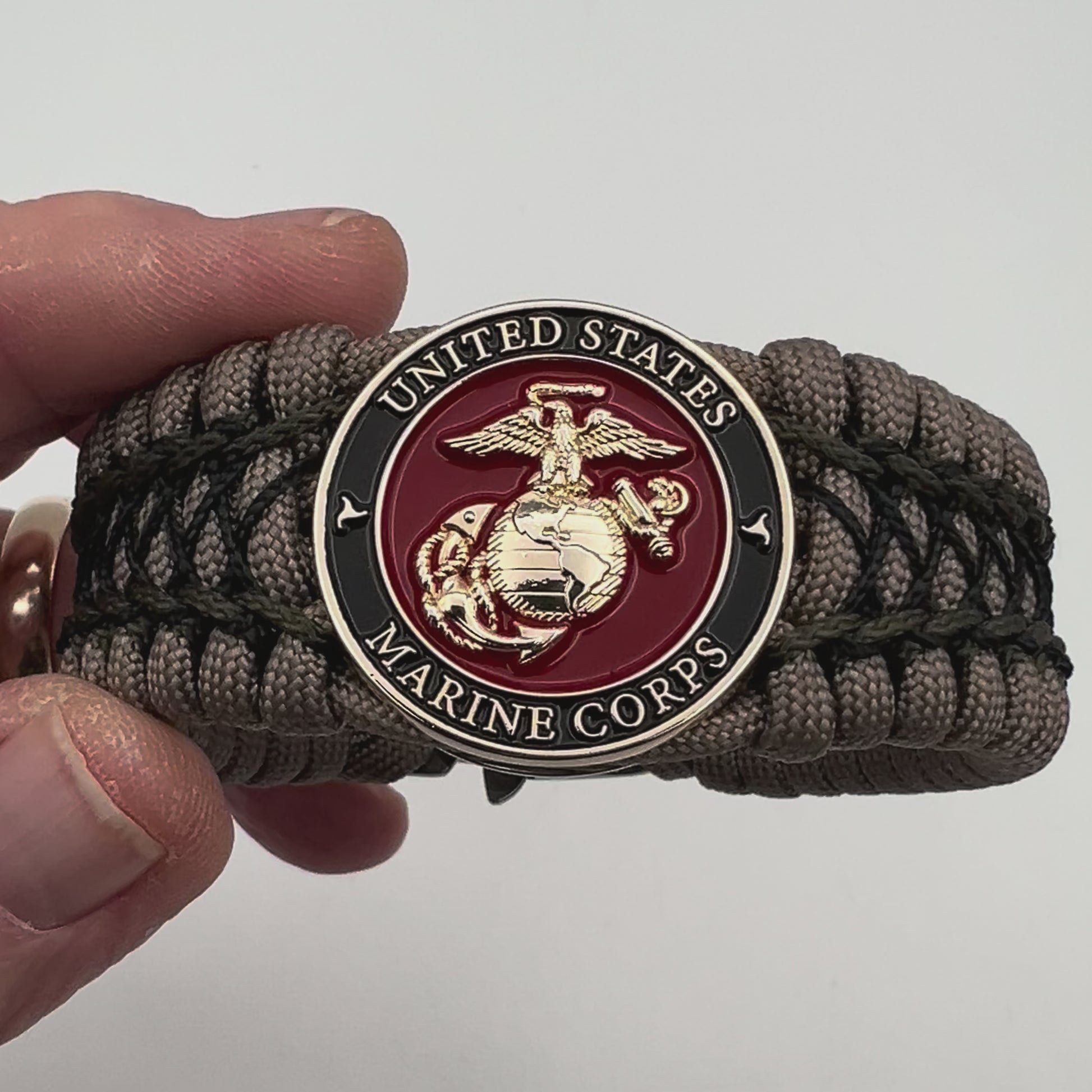 Thick, wide, rigid and comfortable braided United States Marine Corps bracelet featuring a 24K gold plated USMC Eagle Globe and Anchor medallion, a gold Cobra style tactical buckle and woven with tan 550 paracord, olive drab micro and black nano cord.