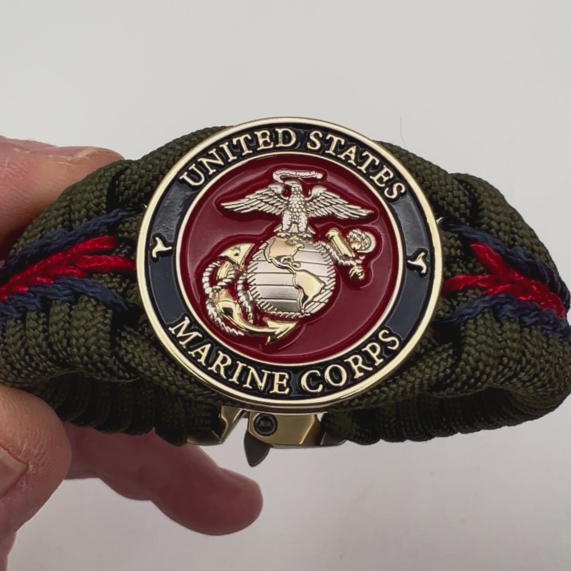 Thick, semi-rigid and comfortable braided United States Marine Corps bracelet featuring a 24K gold and silver plated USMC officer Eagle Globe and Anchor medallion, a gold Cobra style tactical buckle and woven with olive drab 550 and Imperial red and gold micro paracord.
