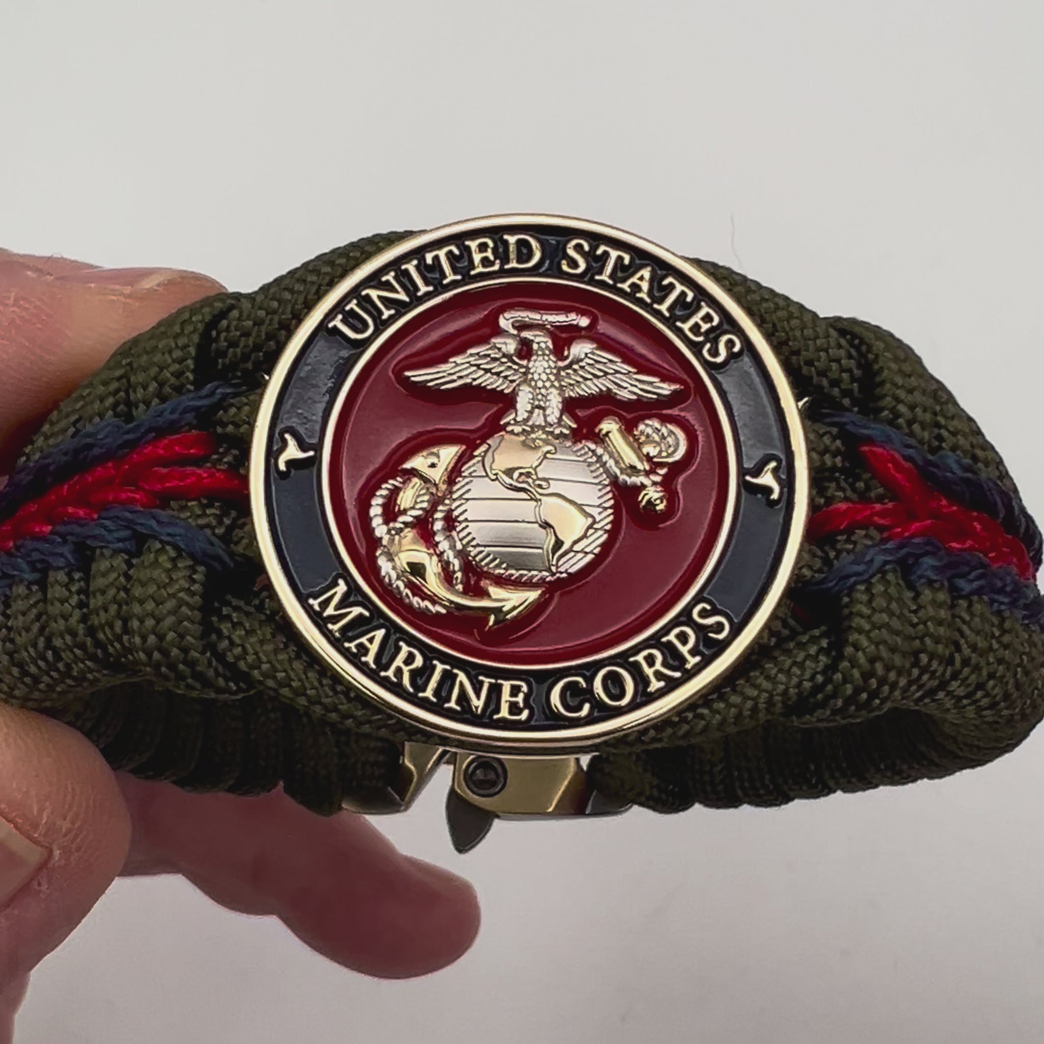 Thick, semi-rigid and comfortable braided United States Marine Corps bracelet featuring a 24K gold and silver plated USMC officer Eagle Globe and Anchor medallion, a gold Cobra style tactical buckle and woven with olive drab 550 and Imperial red and gold micro paracord.