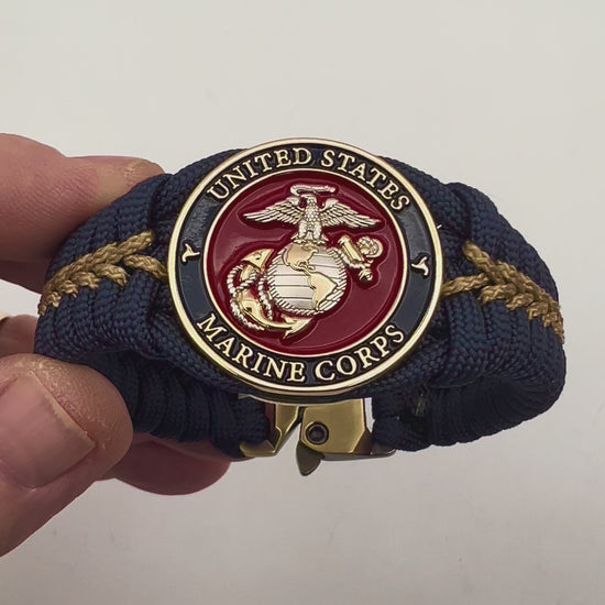 Thick and comfortable braided United States Marine Corps bracelet featuring a 24K gold and silver plated USMC officer Eagle Globe and Anchor medallion, a Cobra style tactical buckle and woven with Navy blue and gold paracord.