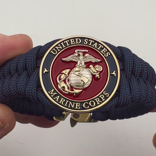 Thick and comfortable braided United States Marine Corps bracelet featuring a 24K gold and silver plated USMC officer Eagle Globe and Anchor medallion, a Cobra style tactical buckle and woven with Navy blue paracord.