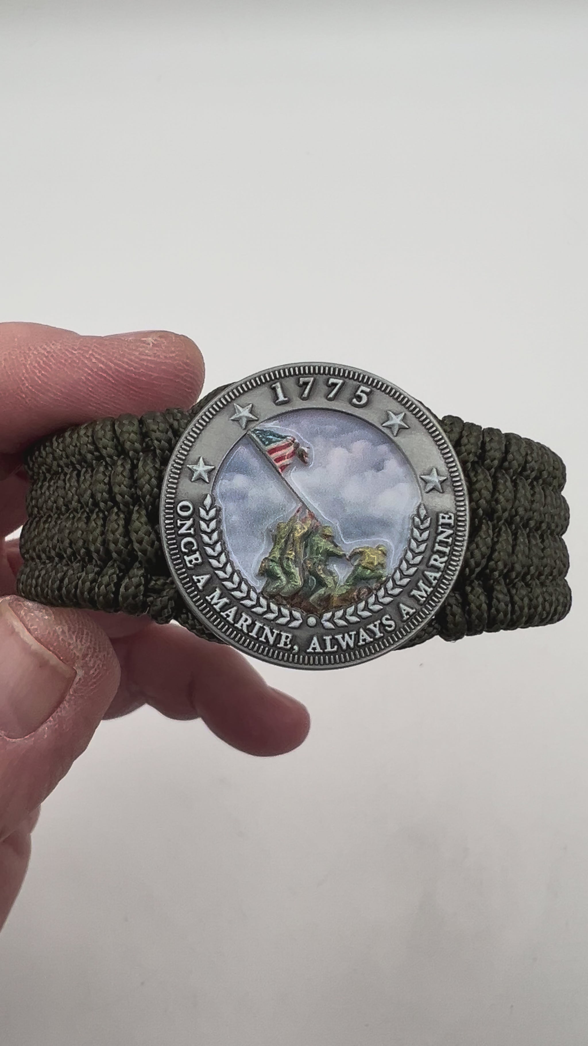 Thin, wide, flexible and comfortable braided United States Marine Corps Iwo Jima bracelet featuring an antique silver plated UV painted Iwo Jima flag raising medallion, a silver Cobra style tactical buckle and woven with olive drab Type-1 paracord.