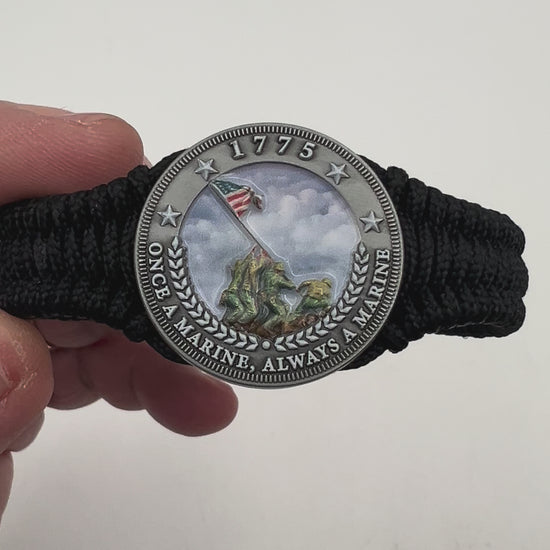 Thin, narrow and comfortable braided United States Marine Corps Iwo Jima bracelet featuring an antique silver plated UV painted Iwo Jima flag raising medallion, a black Cobra style tactical buckle and woven with black type-1 paracord.