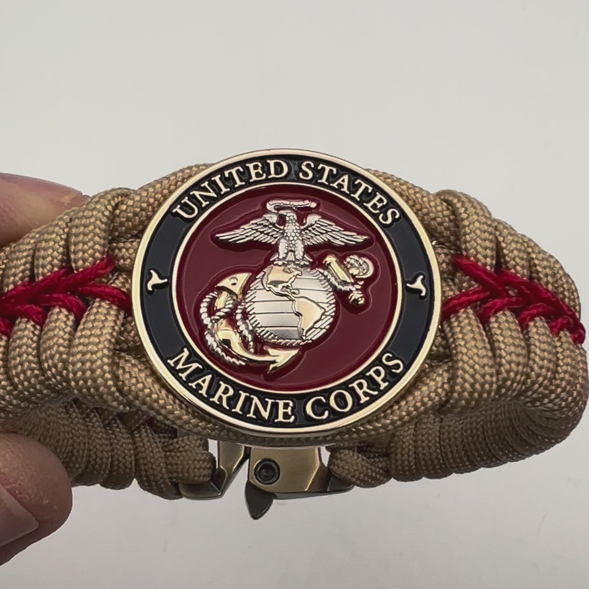 Thick and comfortable braided United States Marine Corps bracelet featuring a 24K gold and silver plated USMC officer Eagle Globe and Anchor medallion, a Cobra style tactical buckle and woven with gold 550 and Imperial red micro paracord.
