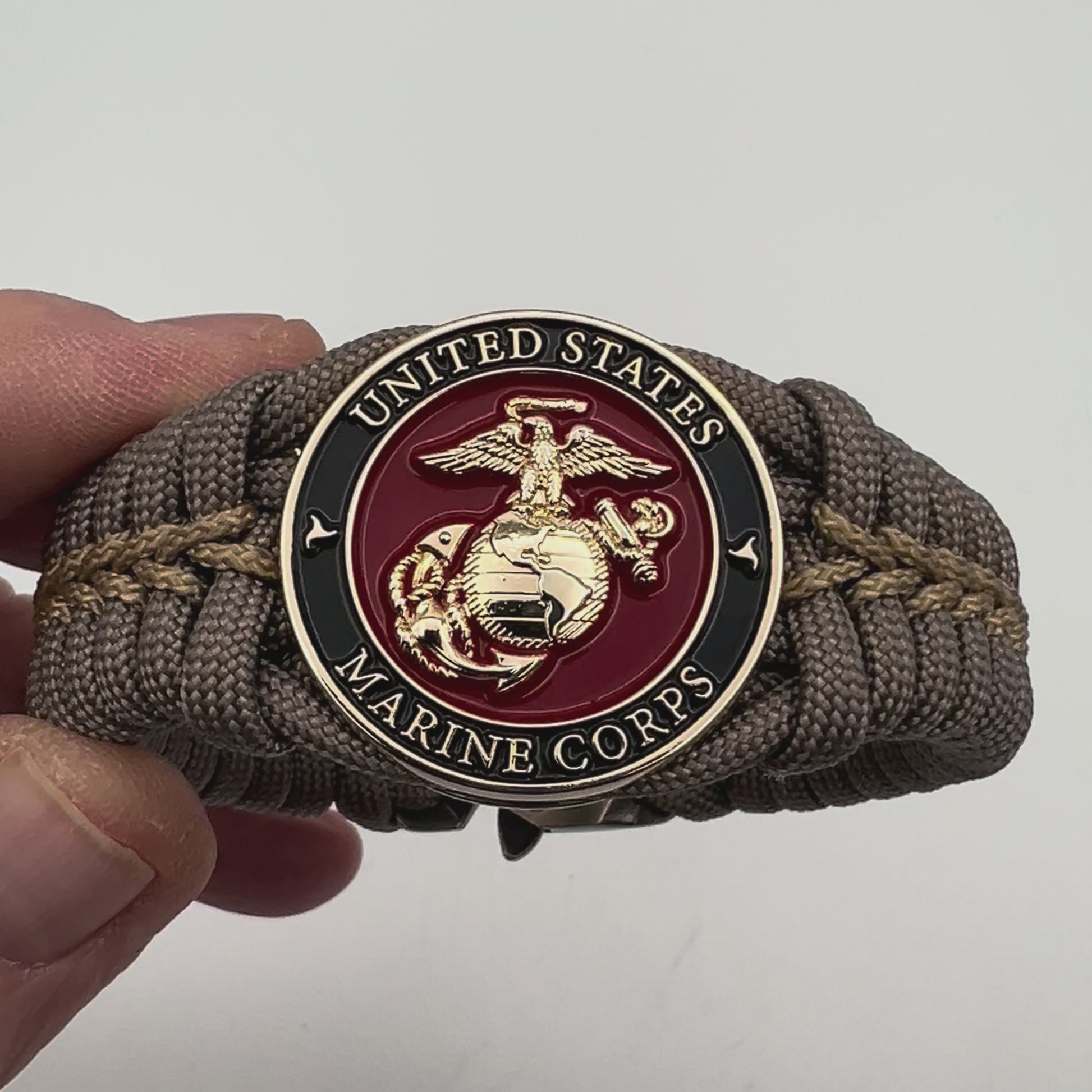 Thick, semi-rigid and comfortable braided United States Marine Corps bracelet featuring a 24K gold plated USMC Eagle Globe and Anchor medallion, a gold Cobra style tactical buckle and woven with tan 550 paracord and gold micro cord.