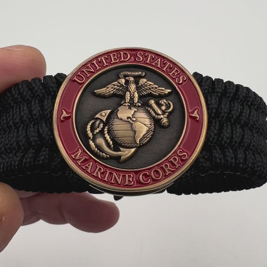 Thin, medium wide, very thin and flexible and comfortable braided United States Marine Corps bracelet featuring a 24K antique gold plated USMC Eagle Globe and Anchor medallion, a black Cobra style tactical buckle and woven with black Type-1 paracord.