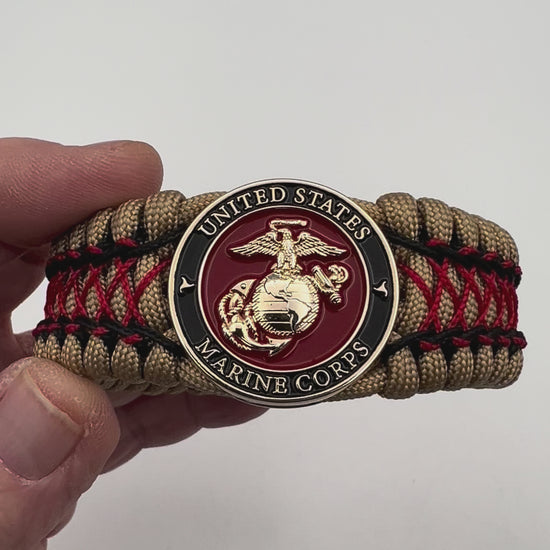 Thick, wide, rigid and comfortable braided United States Marine Corps bracelet featuring a 24K gold plated USMC Eagle Globe and Anchor medallion, a gold Cobra style tactical buckle and woven with gold 550 paracord and Imperial Red micro and black nano cord.