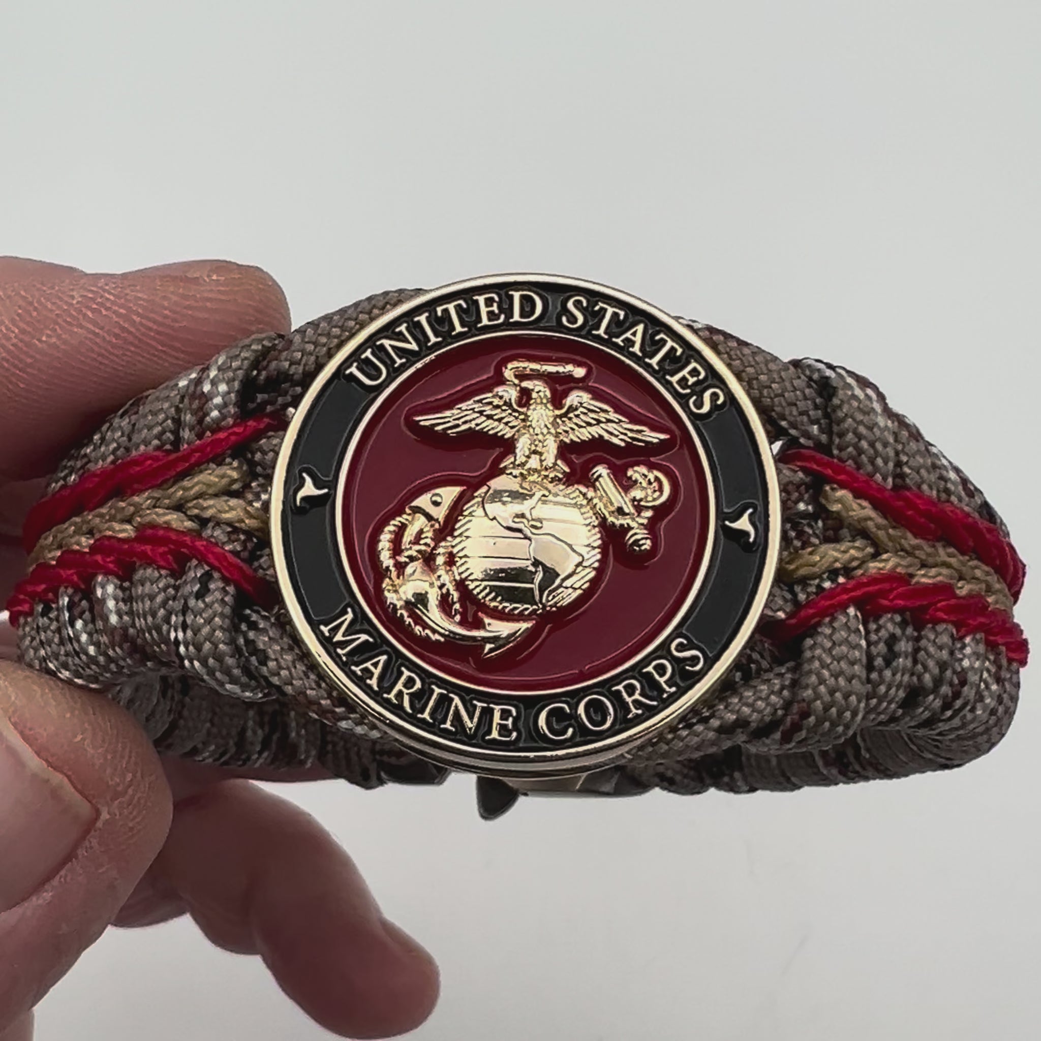 Thick, rigid and comfortable braided United States Marine Corps bracelet featuring a 24K gold plated USMC Eagle Globe and Anchor medallion, a gold Cobra style tactical buckle and woven with Desert Camo 550 paracord and Imperial Red and Gold micro cord.