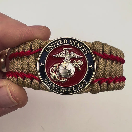 Thick and comfortable braided United States Marine Corps bracelet featuring a 24K gold and silver plated USMC officer Eagle Globe and Anchor medallion, a gold Cobra style tactical buckle and woven with gold 550 paracord and Imperial Red micro cord.