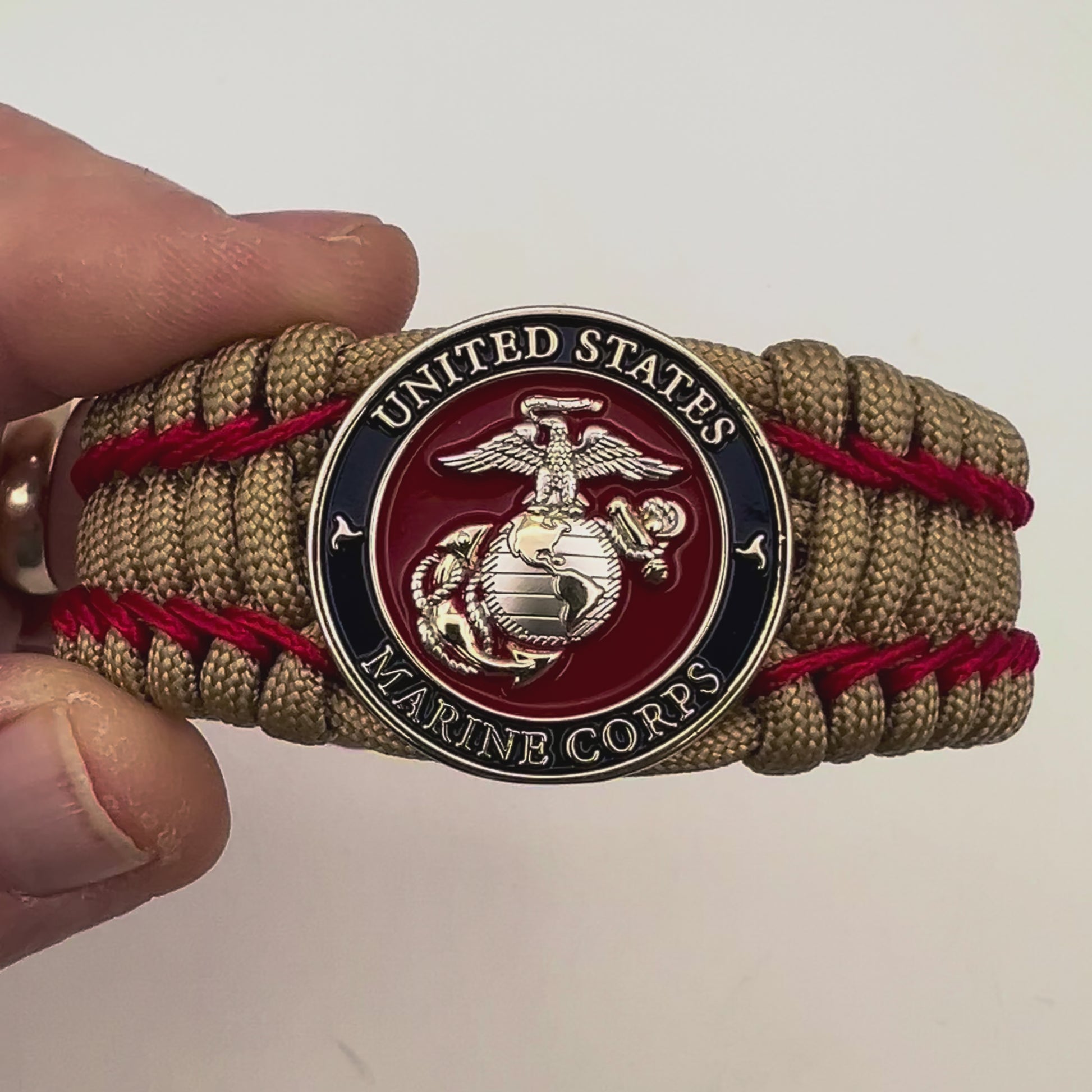 Thick and comfortable braided United States Marine Corps bracelet featuring a 24K gold and silver plated USMC officer Eagle Globe and Anchor medallion, a gold Cobra style tactical buckle and woven with gold 550 paracord and Imperial Red micro cord.