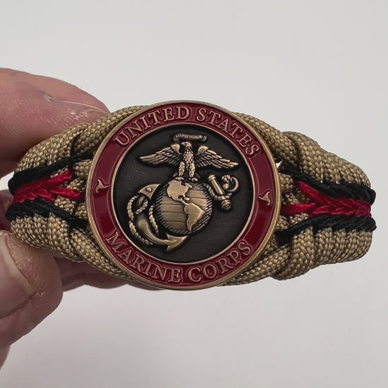 Thick, medium width, rigid and comfortable braided United States Marine Corps bracelet featuring a 24K antique gold plated USMC Eagle Globe and Anchor medallion, a gold Cobra style tactical buckle and woven with gold 550 paracord and Imperial red and black micro cord.