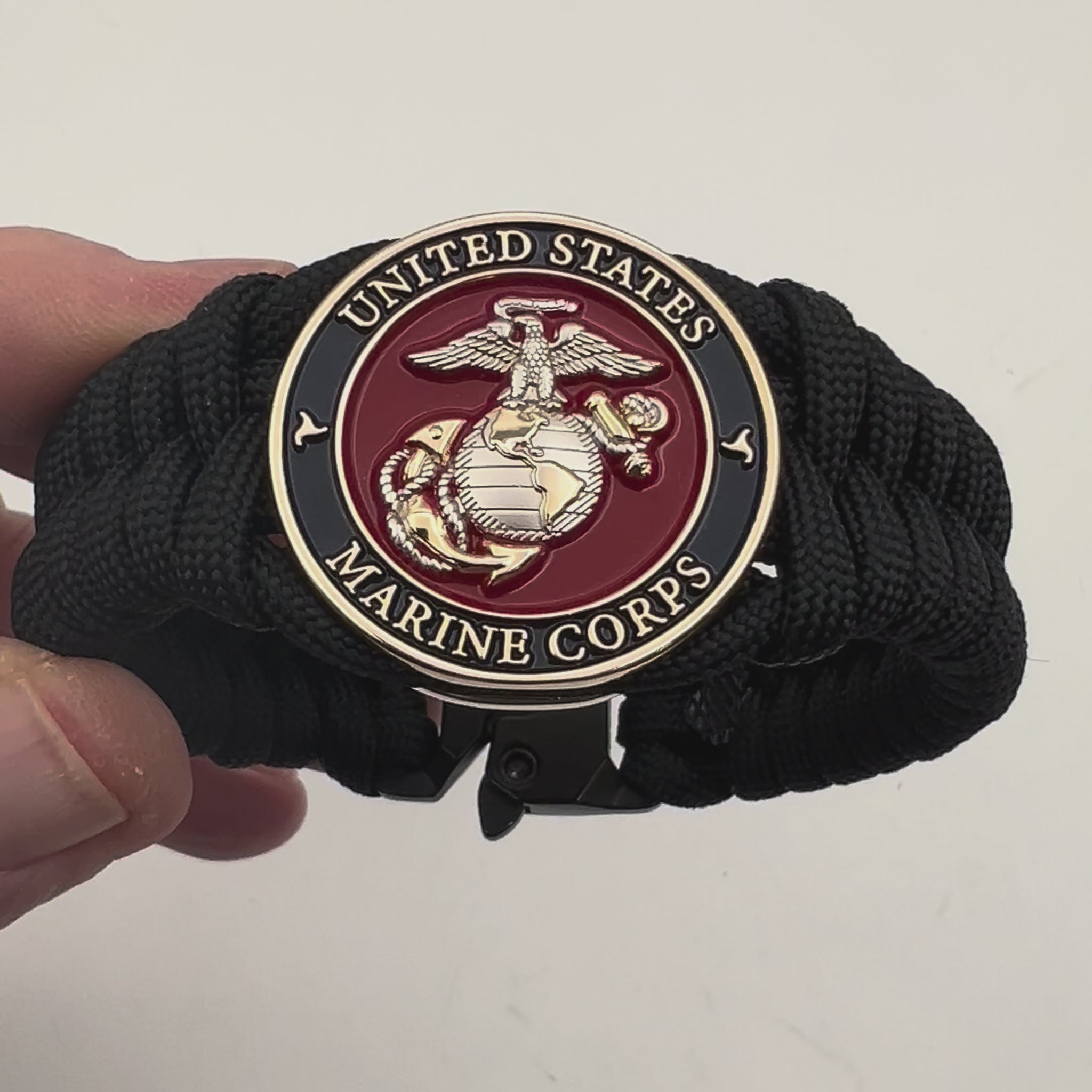 Thick, semi-rigid and comfortable braided United States Marine Corps bracelet featuring a 24K gold and silver plated USMC officer Eagle Globe and Anchor medallion, a black Cobra style tactical buckle and woven with black 550 paracord.
