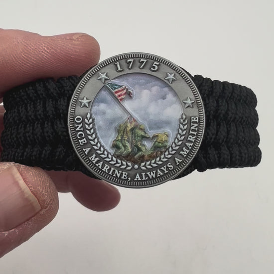 Thin, wide, flexible and comfortable braided United States Marine Corps Iwo Jima bracelet featuring an antique silver plated UV painted Iwo Jima flag raising medallion, a black Cobra style tactical buckle and woven with black Type-1 paracord.